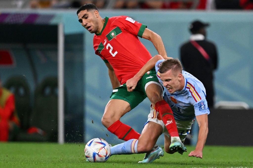 Morocco defender Achraf Hakimi (L) and Spain forward Dani Olmo fight for the ball