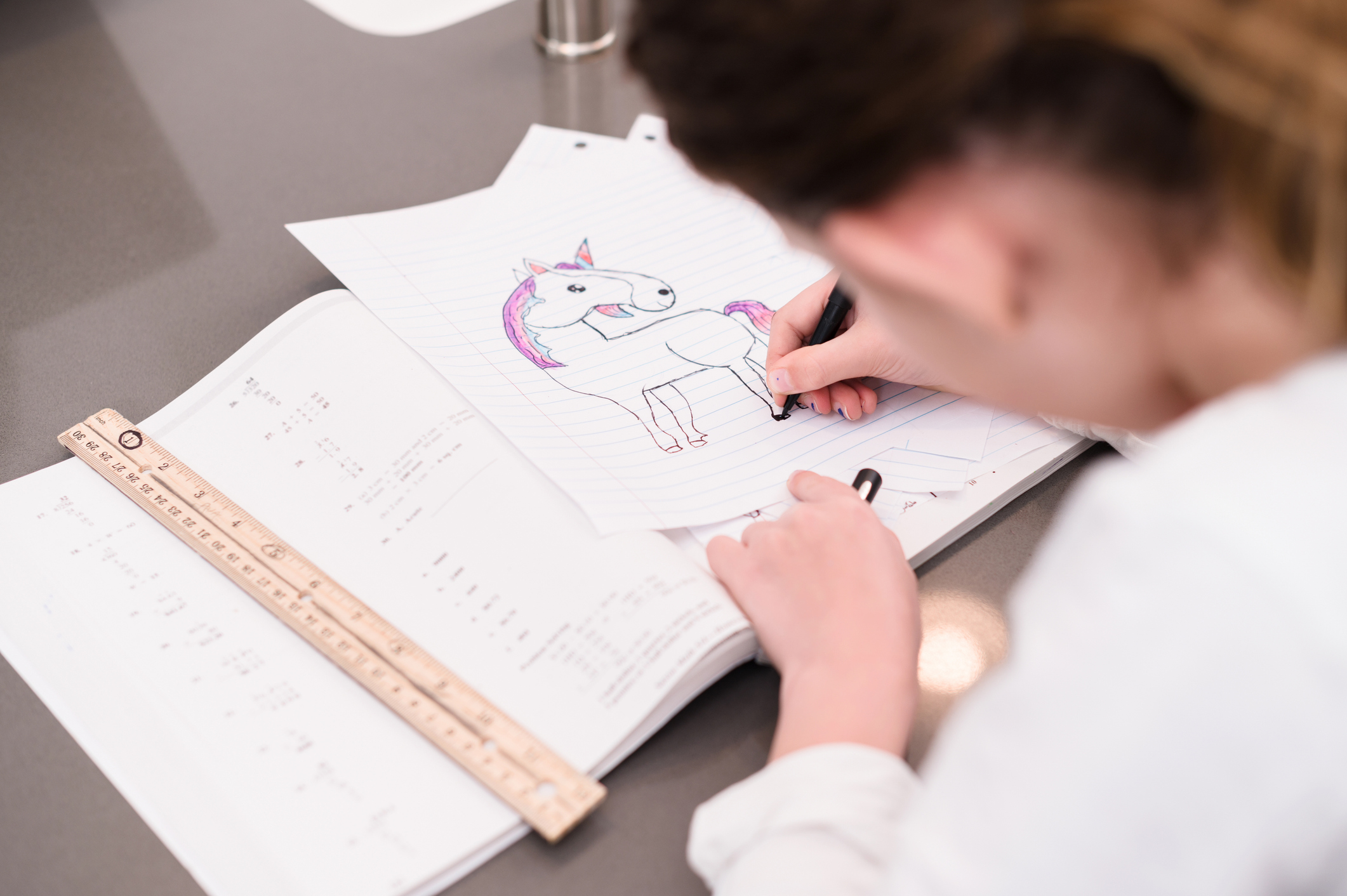 A young girl drawing a unicorn on a paper