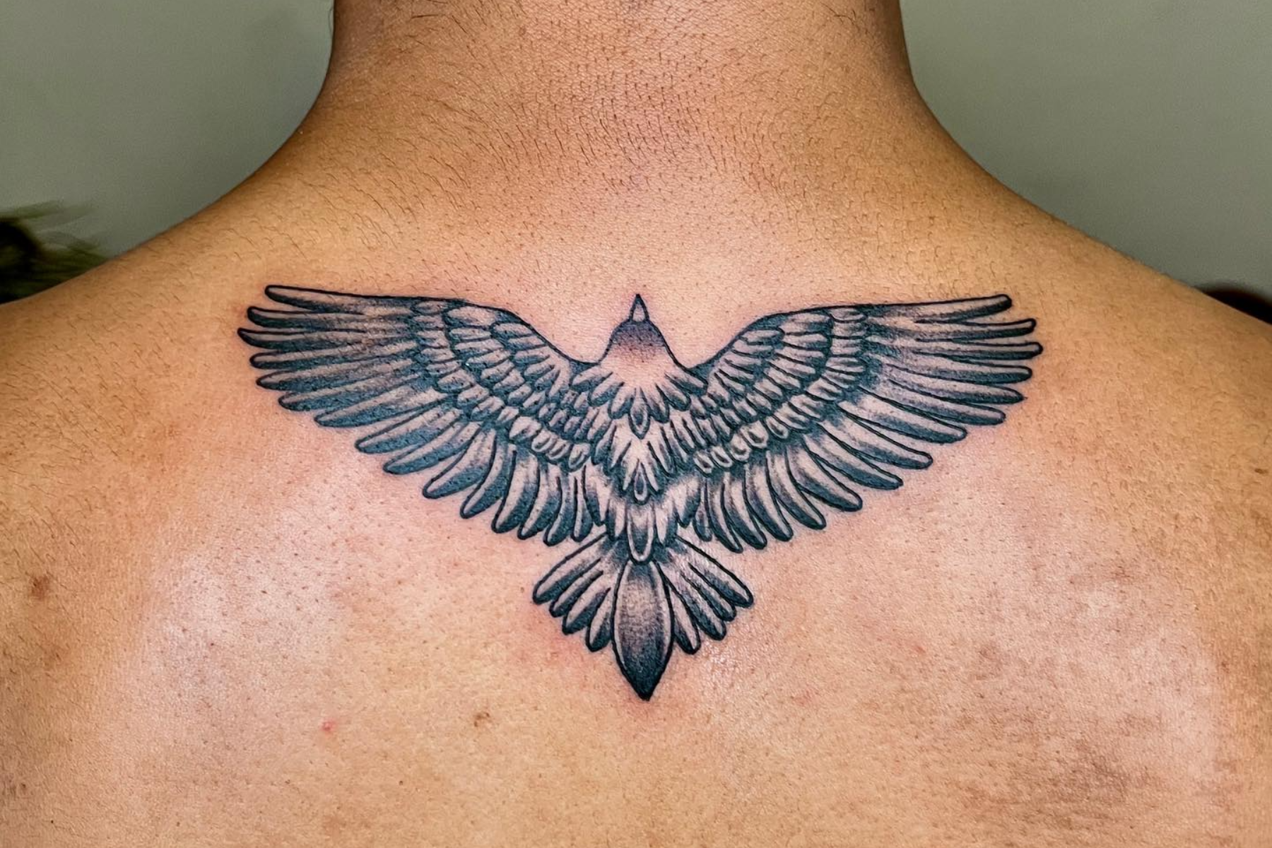 A man has an eagle tattoo on his upper back