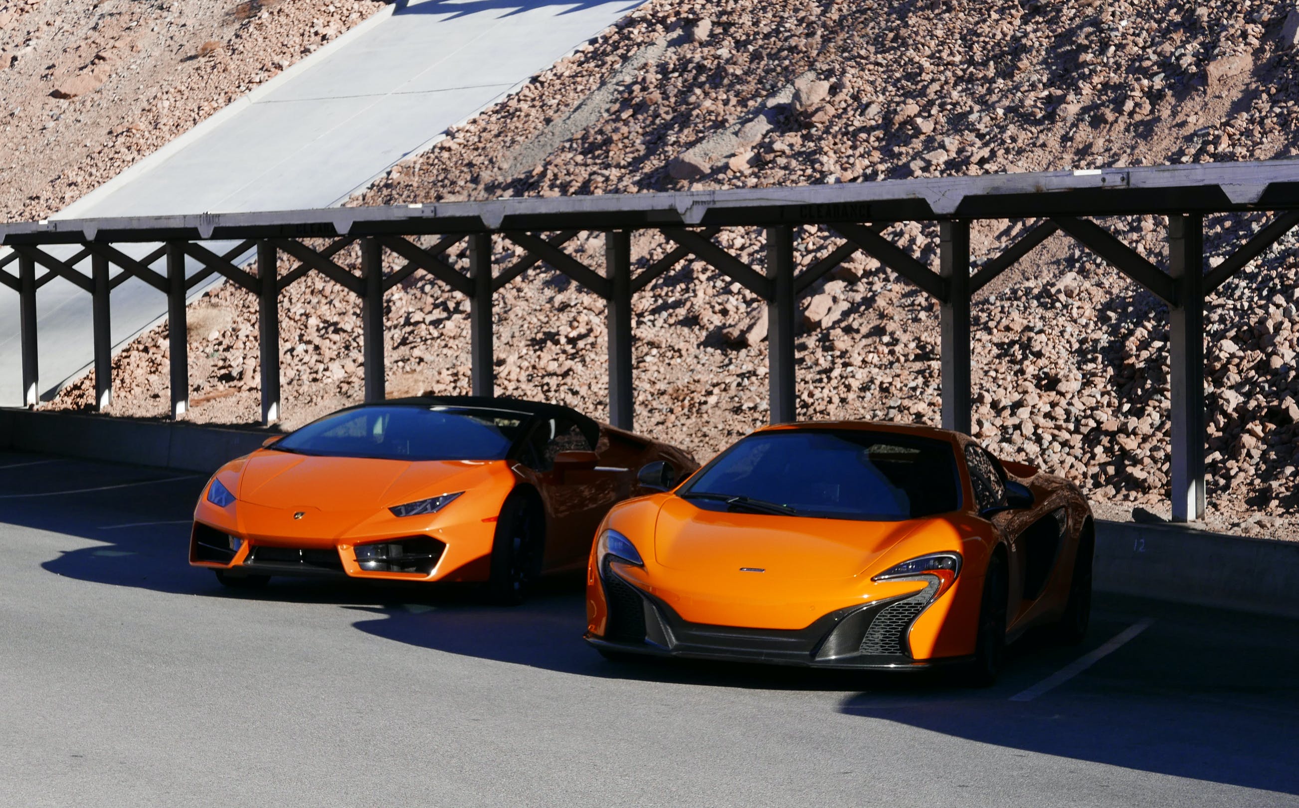 Two orange sports cars at a parking lot