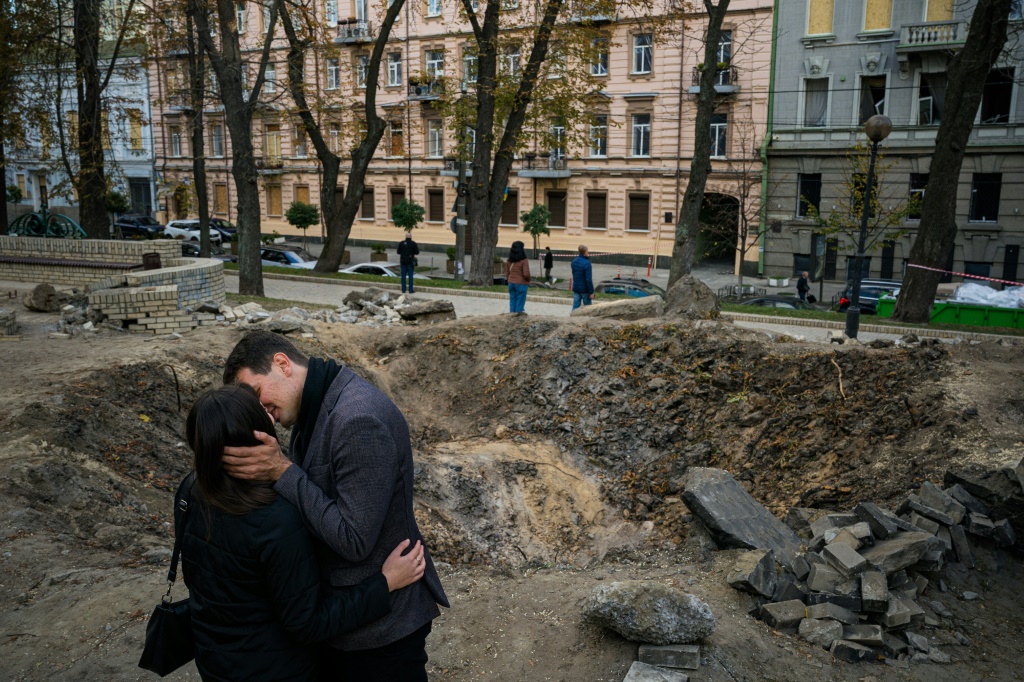 The IMF chief praised the 'incredible resilience of the Ukrainian people. Here a couple kiss by a rocket crater in a park of central Kyiv earlier this month