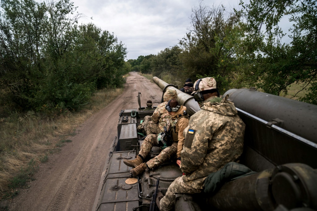 Ukrainian soliders sit on a piece of artillery near the frontline with Russian forces in the south of the country