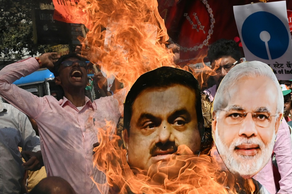 An activist with India's opposition Congress party shouts slogans in Kolkata as he burns an effigy of Prime Minister Narendra Modi and tycoon Gautam Adani to protest against the government's financial policies