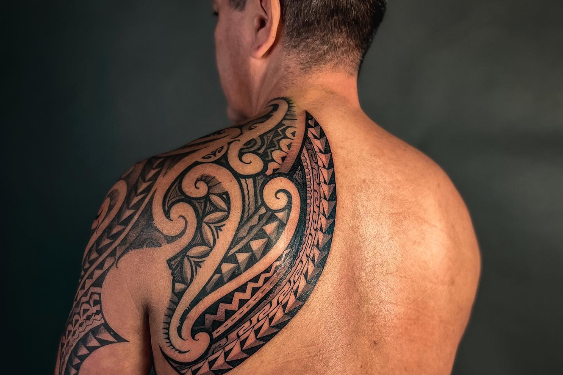 A man has a left back shoulder tattoo