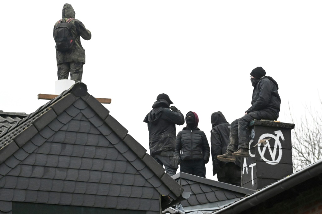 Activists sit on the roof of a squatted house as police move in
