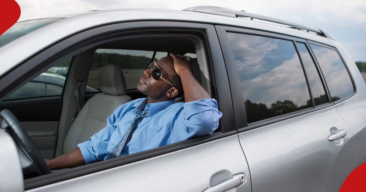 A man sitted in a car while holding his head.