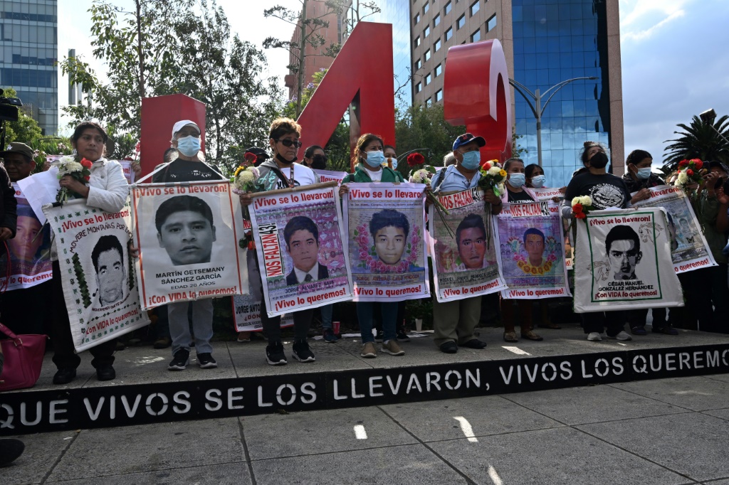 Relatives carry pictures of some of the 43 Mexican students who disappeared in 2014, at a march marking the eighth anniversary of the tragedy