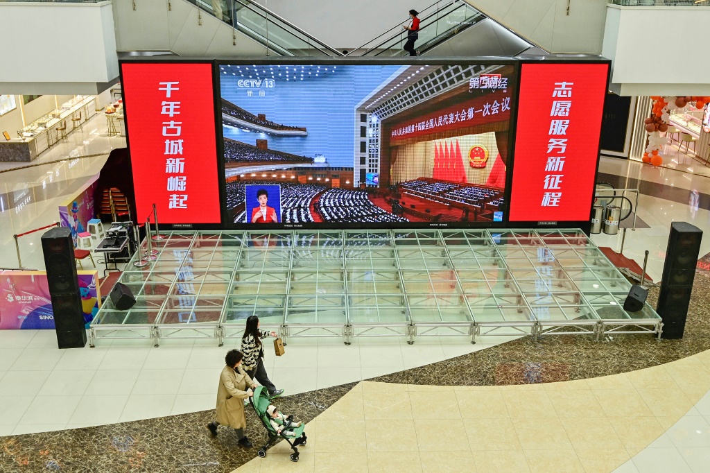 Live coverage of the opening session of the National People's Congress (NPC) is shown at a shopping mall in Qingzhou, China