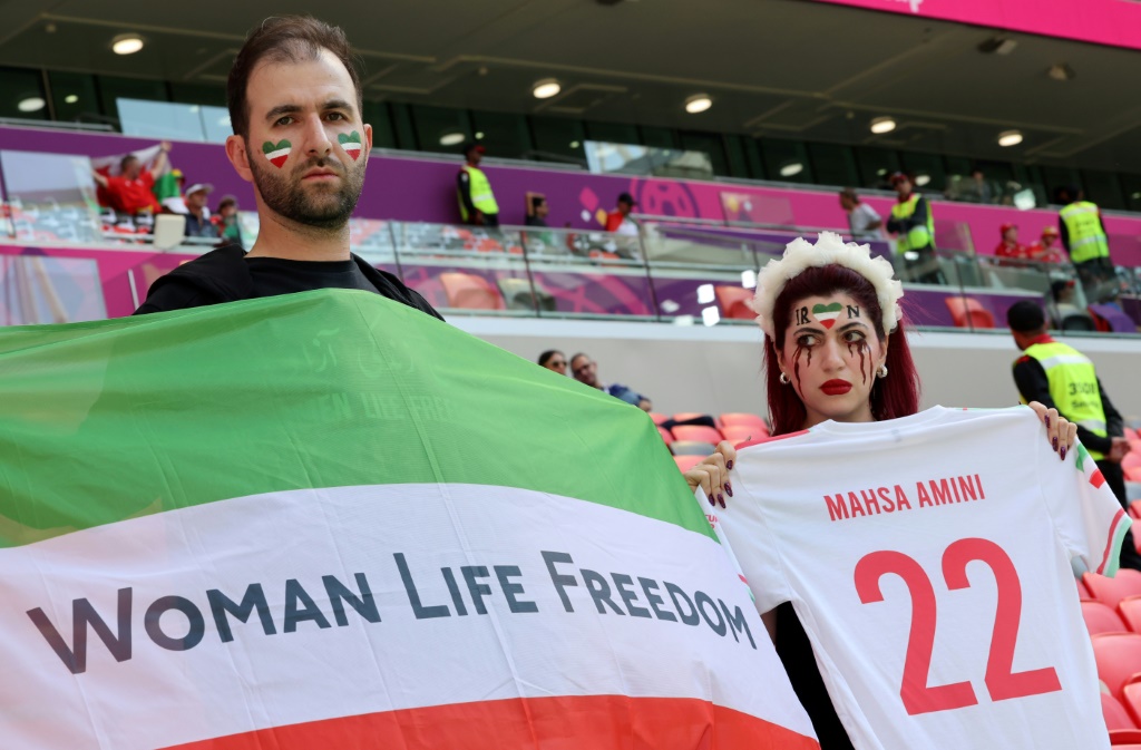 An Iran supporter with make-up suggesting tears of blood holds a football jersey with the name of Mahsa Amini, at the Qatar 2022 World Cup Group on November 25, 2022