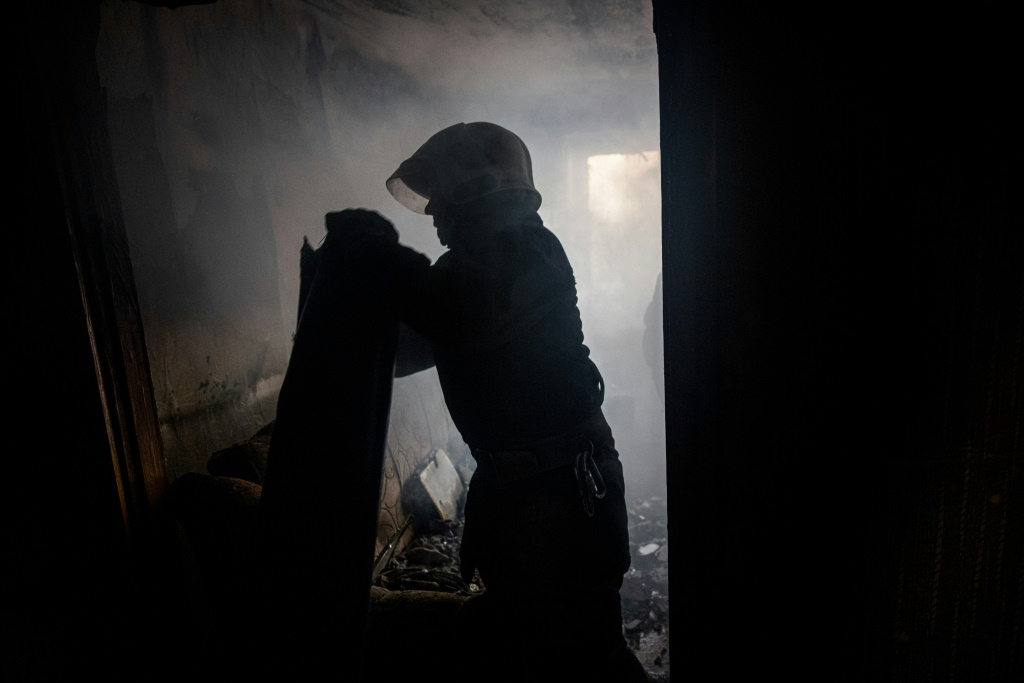 A Ukrainian firefighter removes a piece of a MLRS BM-27 Uragan missile from an apartment in Bakhmut on October 29