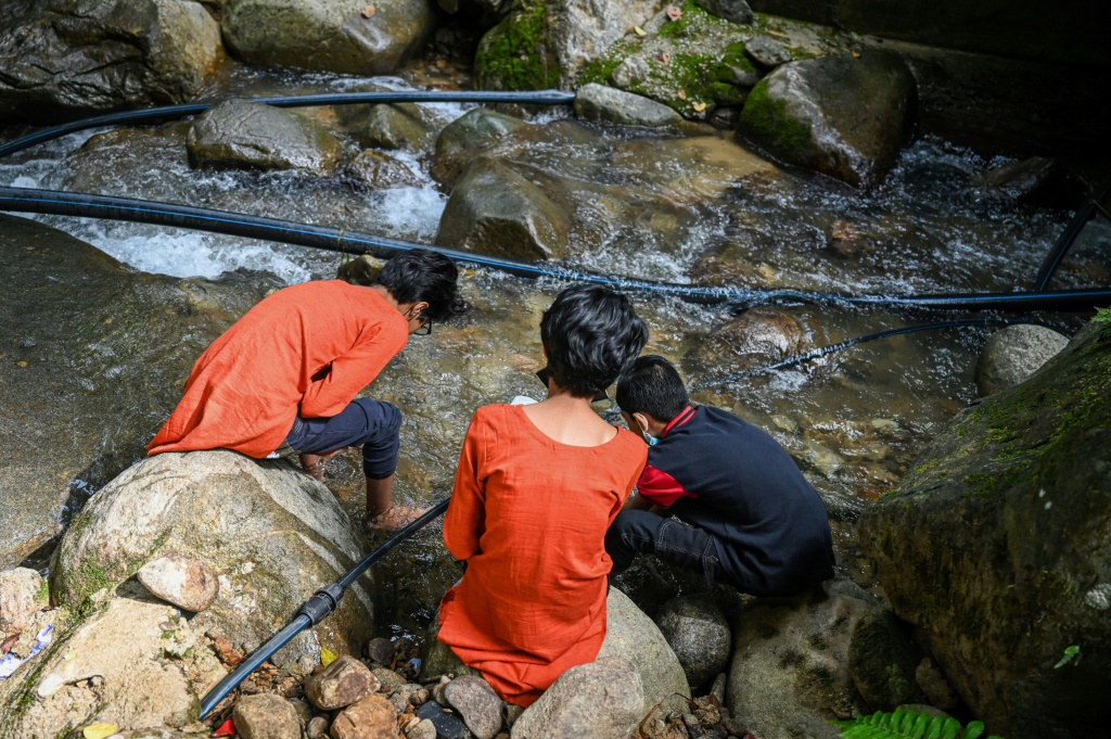 Loh Siew Hong's three children play by a river in Gombak, Malaysia's Selangor state