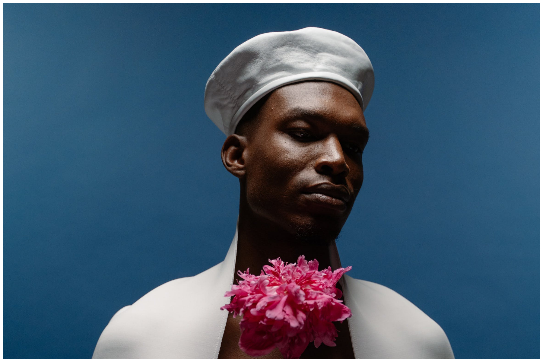 A black male model posing with pink flowers