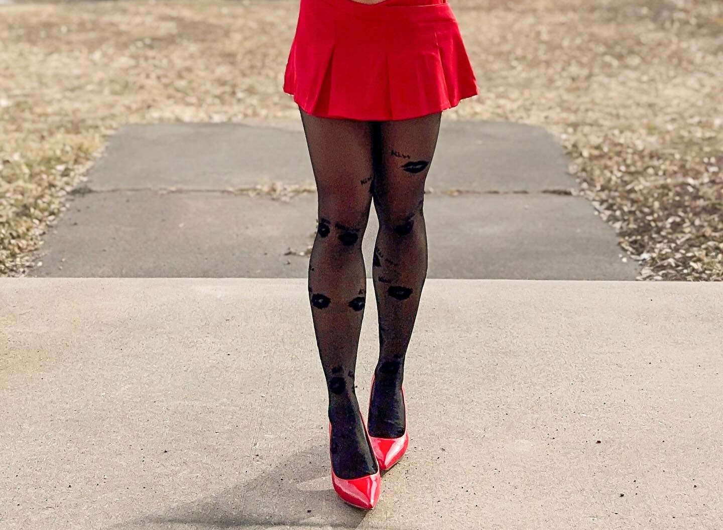 A stylish lady pairs a red mini skirt with a pair of red shoes