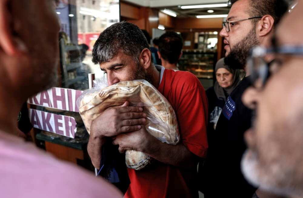 A man walks out of a bakery clutching a bag of subsidised flatbread, as others continue to queue amid a wheat shortage in crisis-hit Lebanon