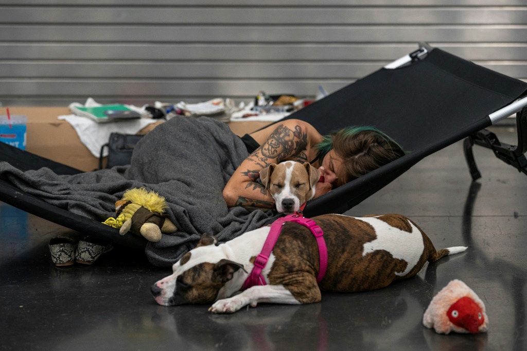 Austun Wilde rests with her two dogs, Bird Is The Wurd and Fenrir at a cooling center in the Oregon Convention Center on June 27, 2021 in Portland; Multnomah County is suing fossil fuel companies for damages caused by climate change