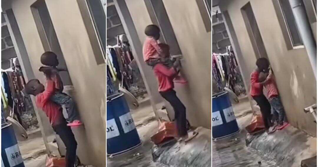 Little boy carries brother to watch television through neighbour's window