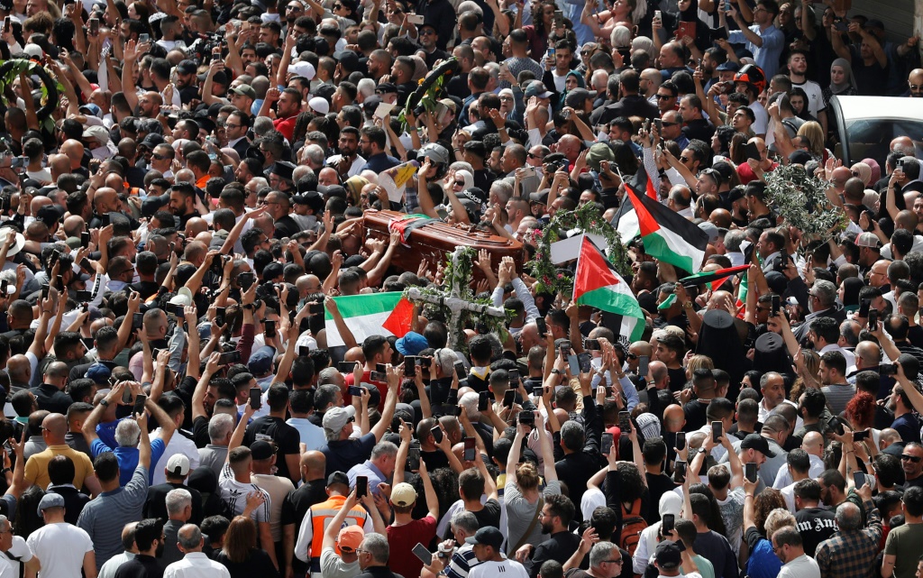 Palestinian mourners wave national flags as they carry the casket of Shireen Abu Akleh during her funeral procession in  Jerusalem on May 13, 2022