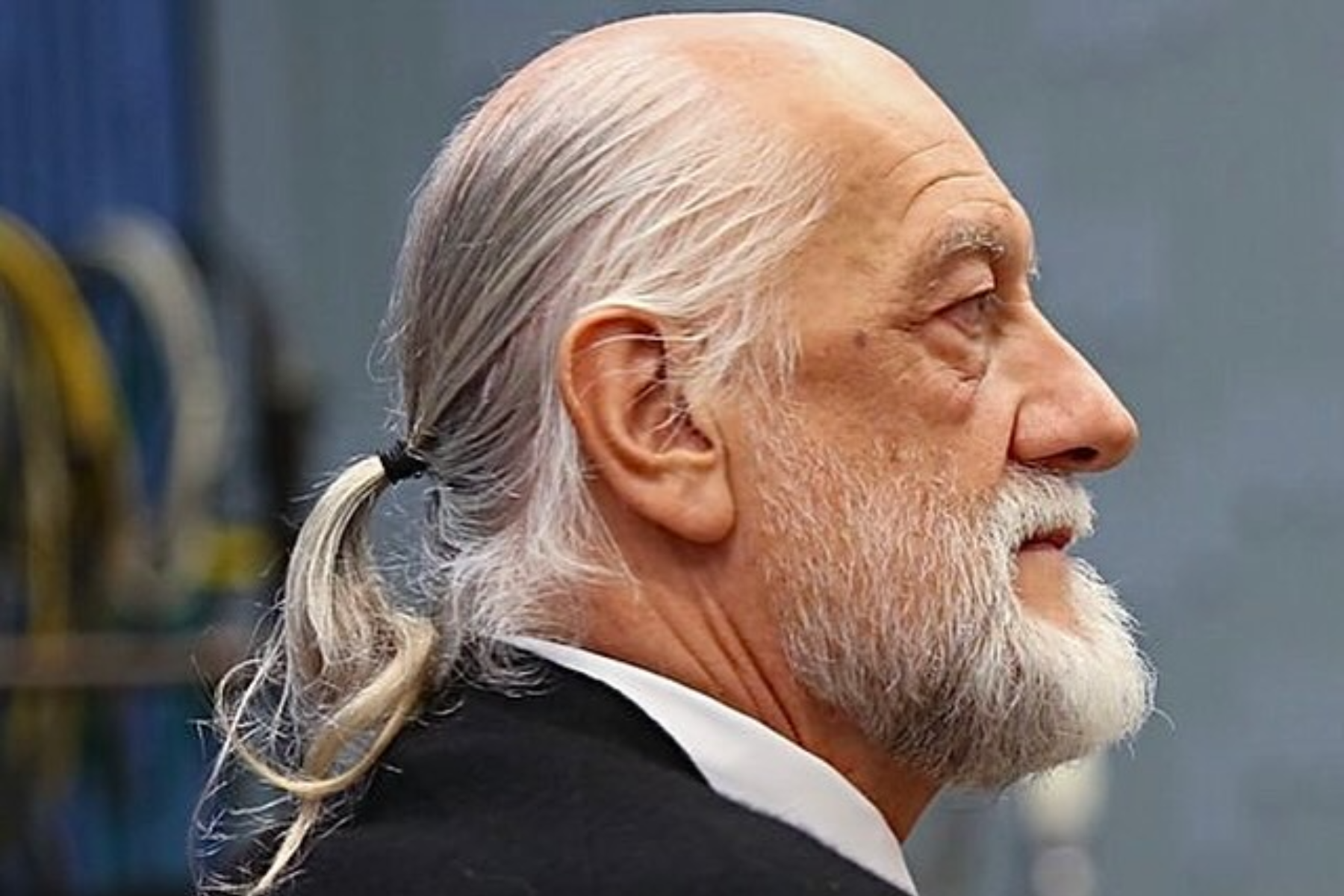 An aged man is rocking a low ponytail style