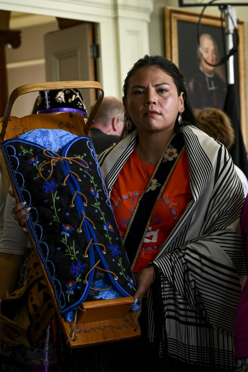 An Indigenous woman carries a traditional baby cradle in memory of Indigenous children, as she arrives to meet Pope Francis in Iqaluit, Nunavut, Canada, on July 29, 2022