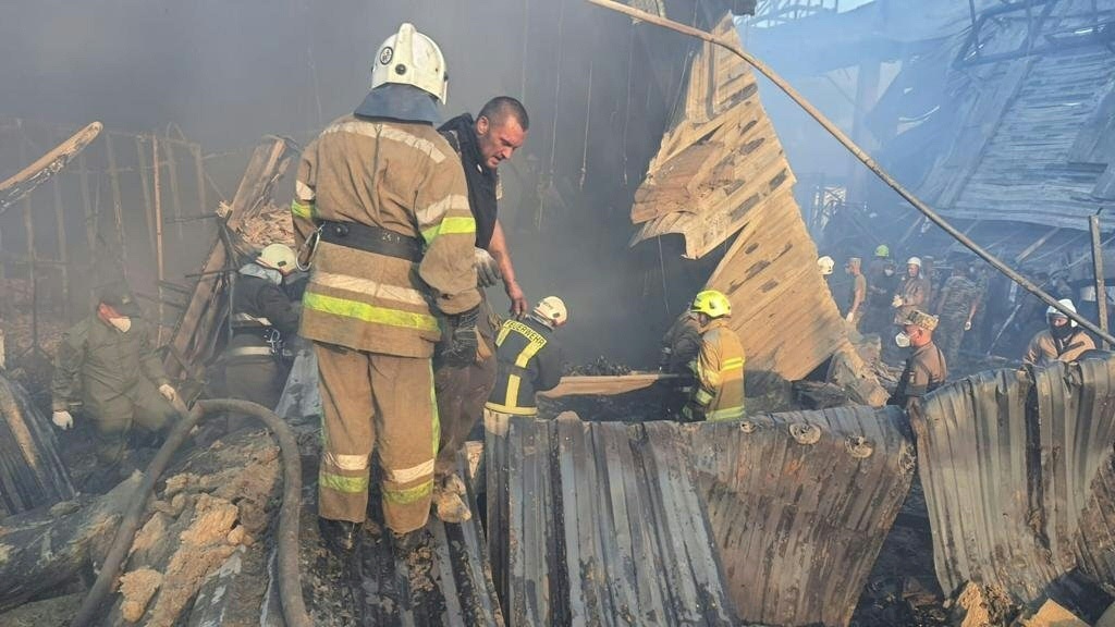 Rescue personnel work amid the smouldering remains of the mall in Kremenchuk