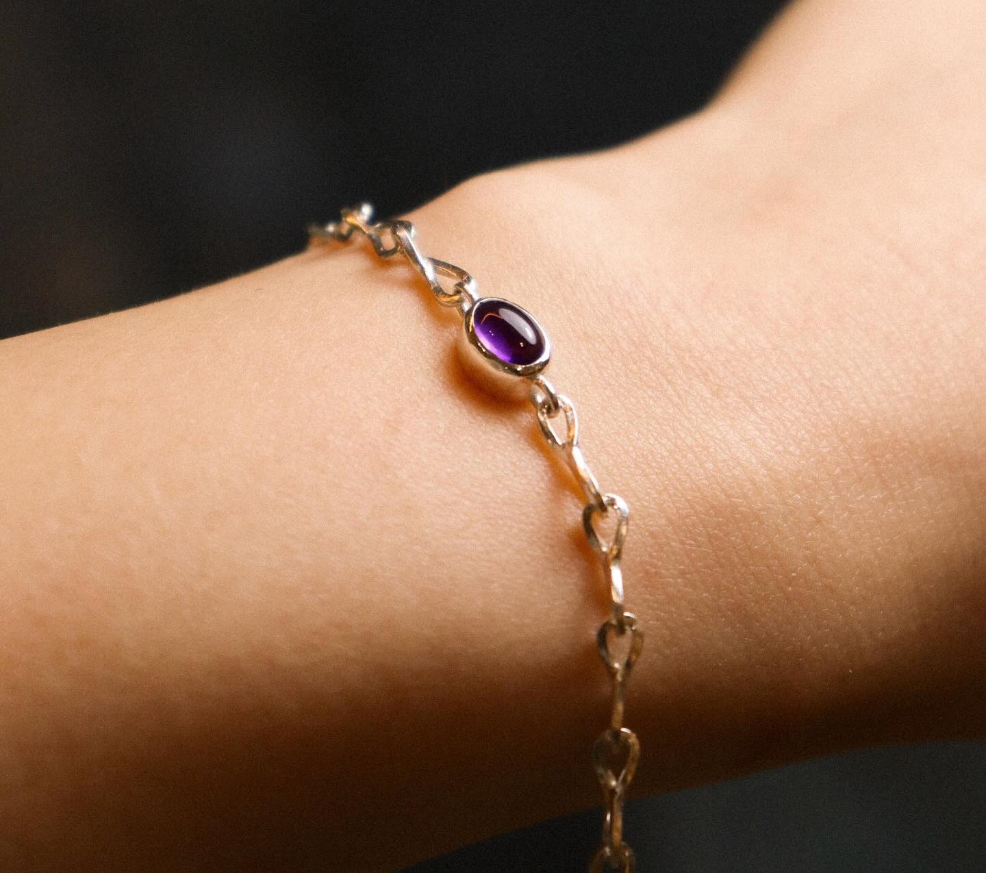 A woman wears a purple birthstone bracelet