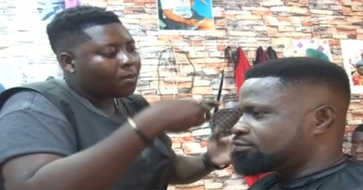 Ghanaian female artisan barbing the hair of a male client