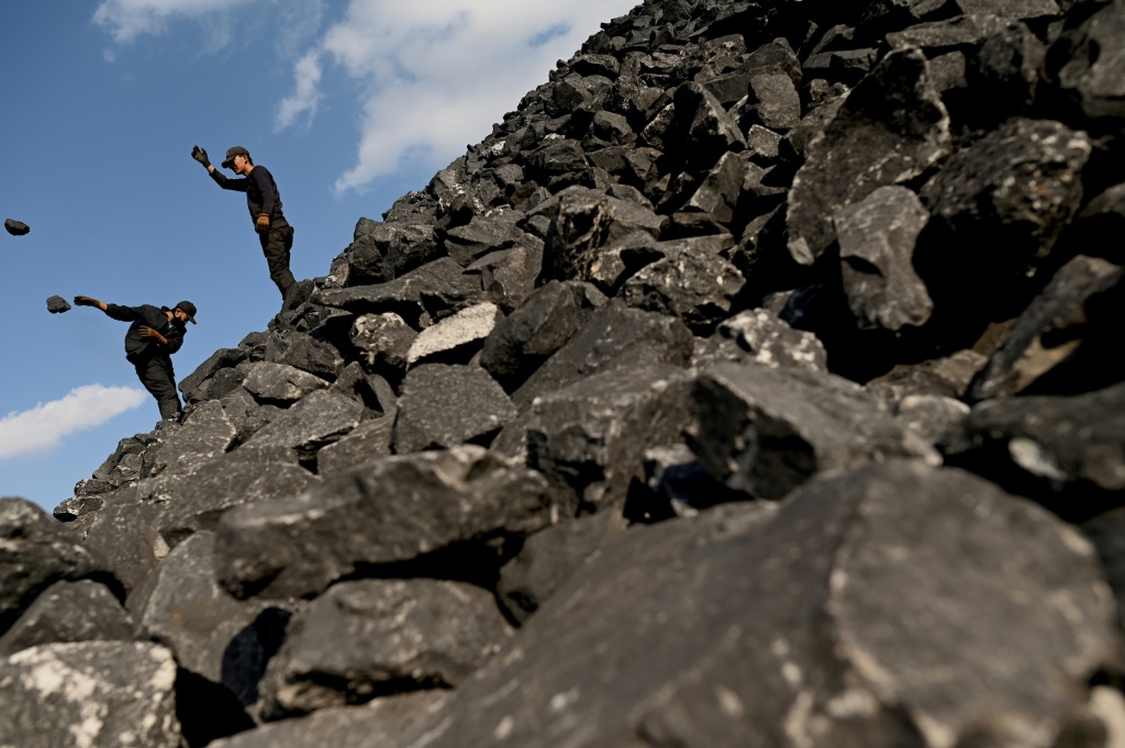 Workers sort coal near a coal mine in Datong, China's northern Shanxi province on November 2, 2021