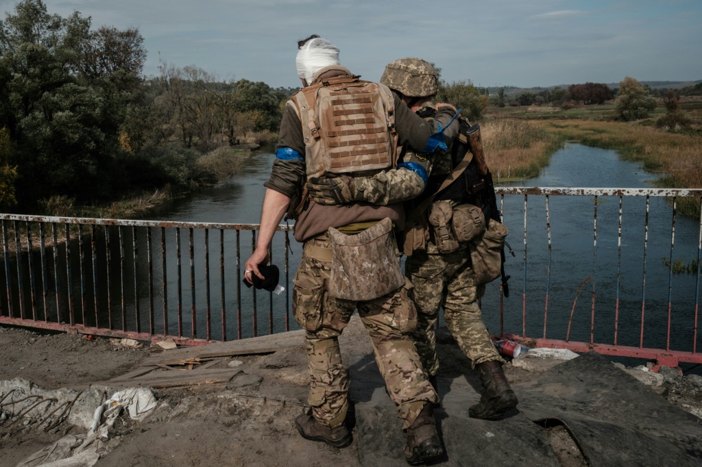 A wounded Ukrainian serviceman crosses a bridge in a recently retaken area near Kharkiv