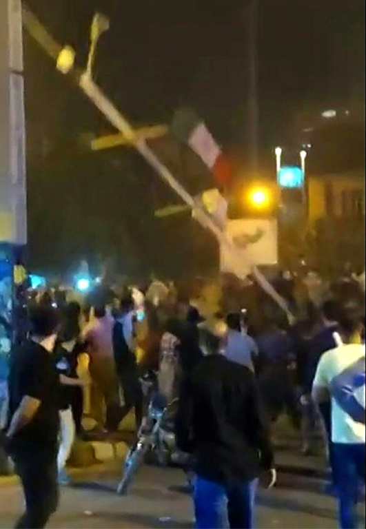This grab from a video made available on the ESN platform shows protesters bring down a flagpole in Saqez city of Iran's Kurdistan province on September 19, 2022