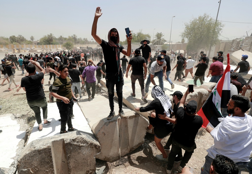 Supporters of the Iraqi cleric Moqtada Sadr celebrate after bringing down concrete barriers leading to the capital Baghdad's high-security Green Zone and the country's parliament