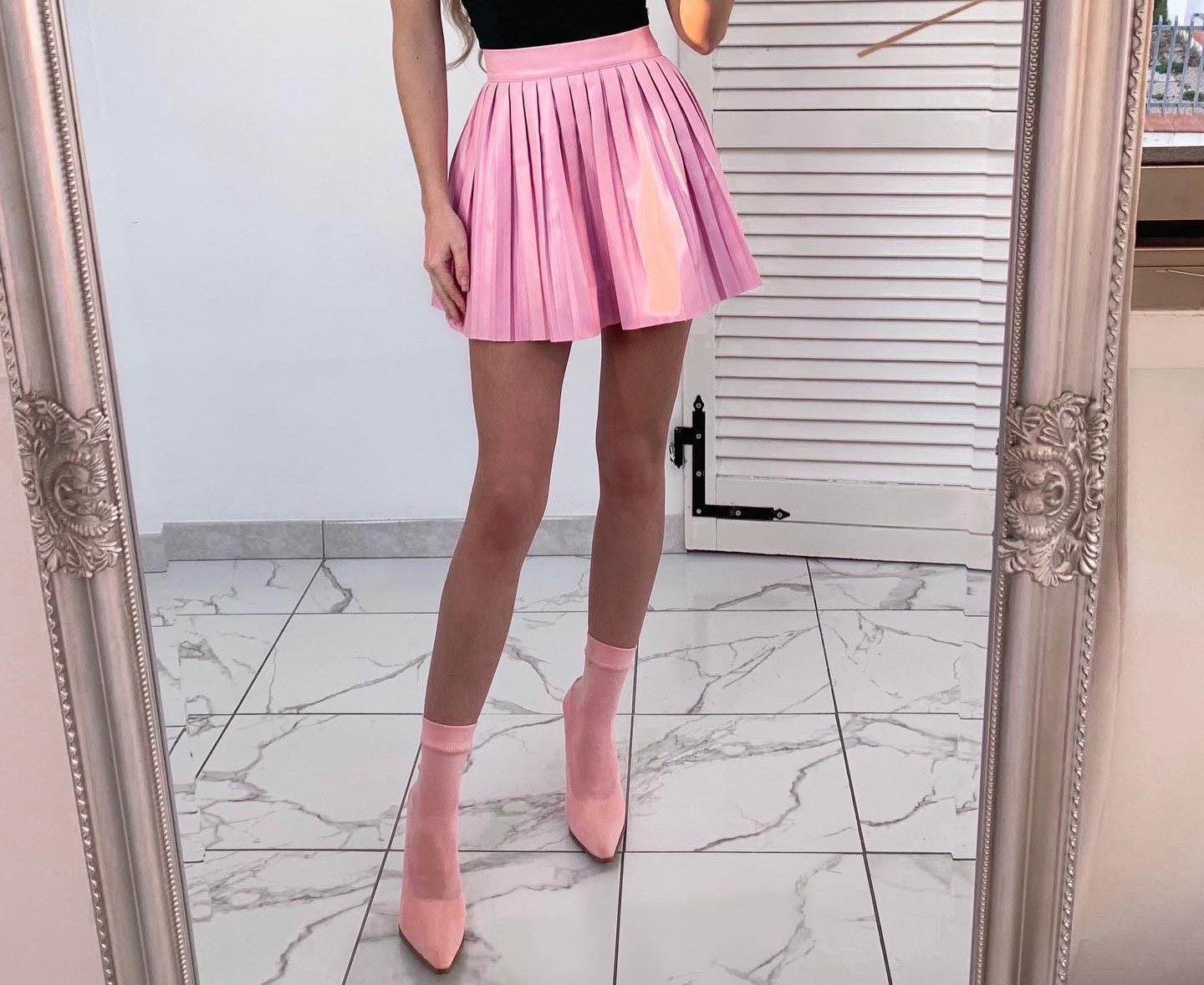 A fashionable woman matches a pink skater skirt with pink boots