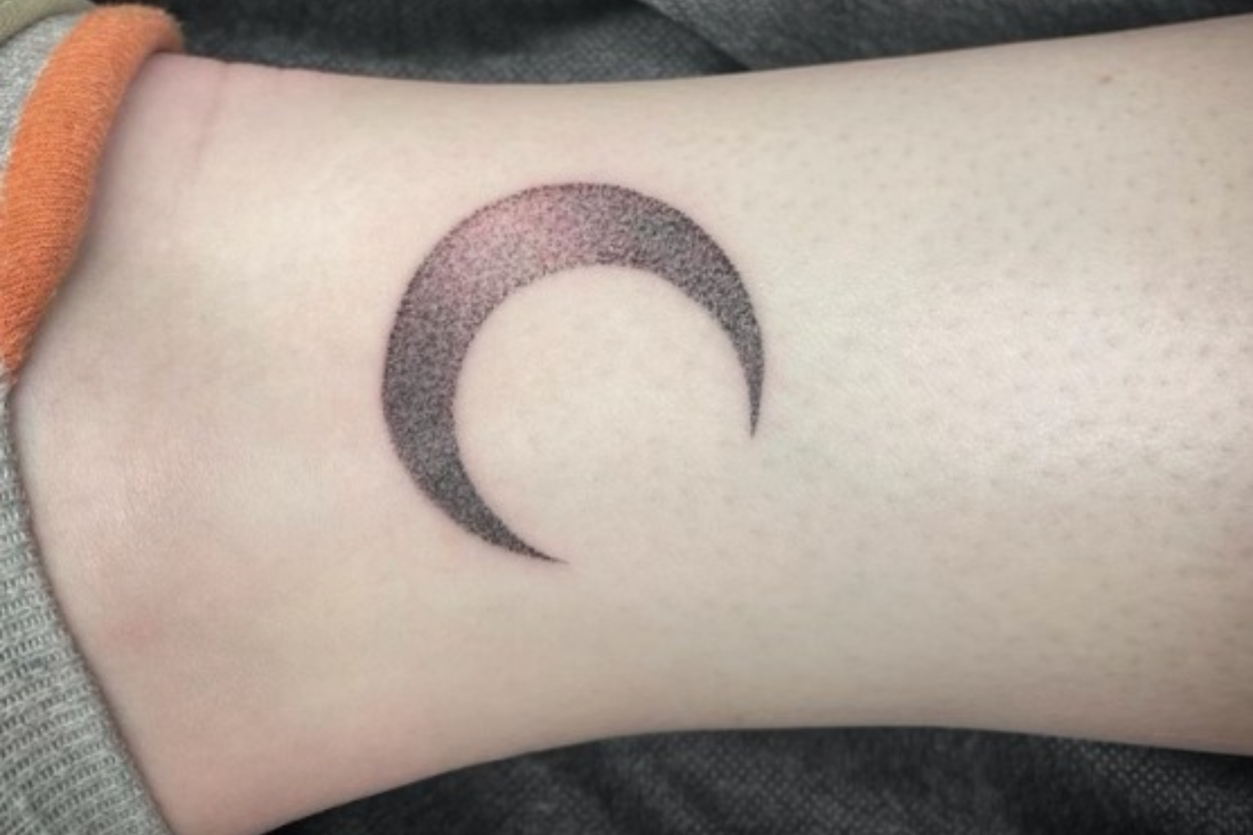 Minimalist moon and wave tattoo on the ankle.