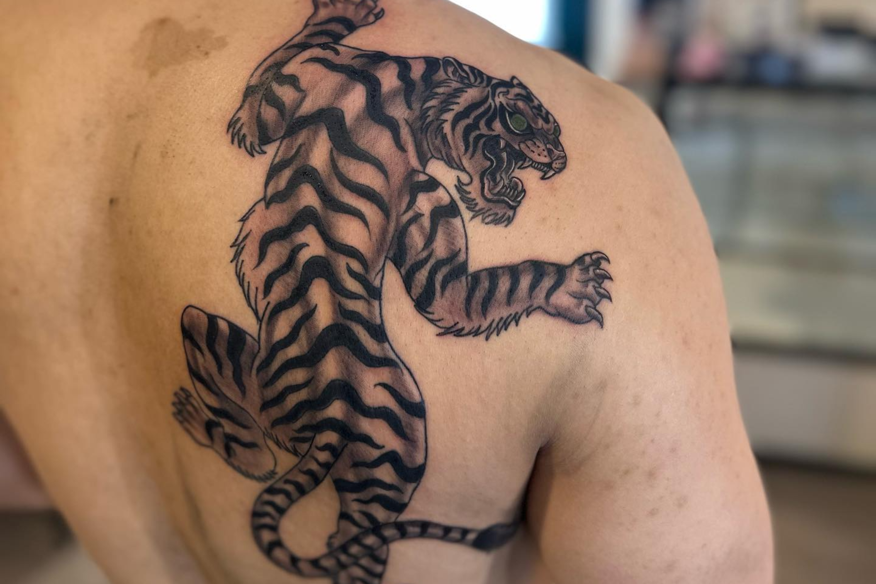 A man has a tiger tattoo on his right shoulder