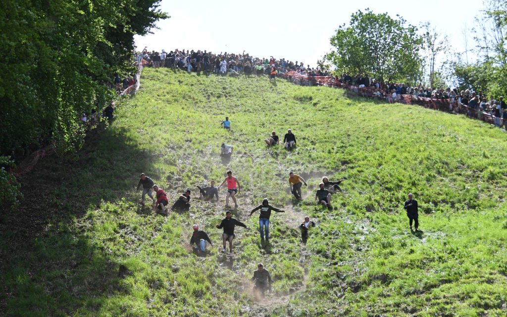 Participants compete in a hill-downhill cheese rolling race in Gloucester, UK