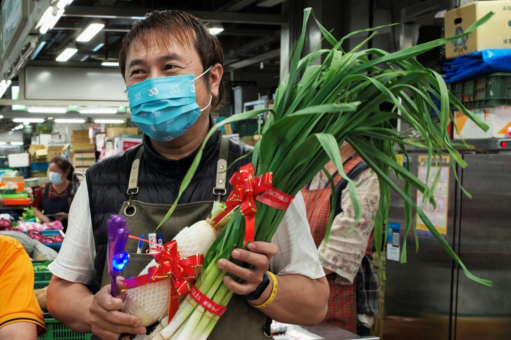 A Taipei greengrocer presents vegetables to a mayoral candidate