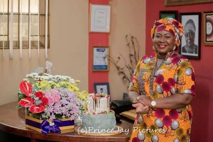 Gifty Anti standing next to a cake and a flower arrangement