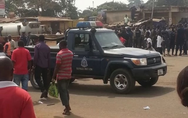 Police vehicle left in the middle of a road and surrounded by upset youth in a part of Ghana