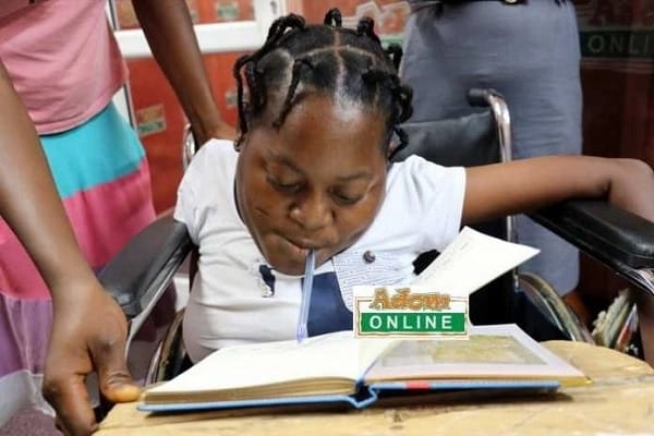 Girl writes BECE exam with pen in mouth