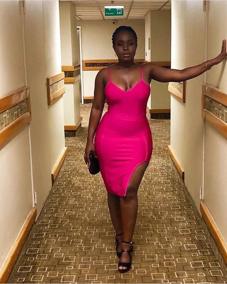 Woman stands in a hallway wearing pink dress