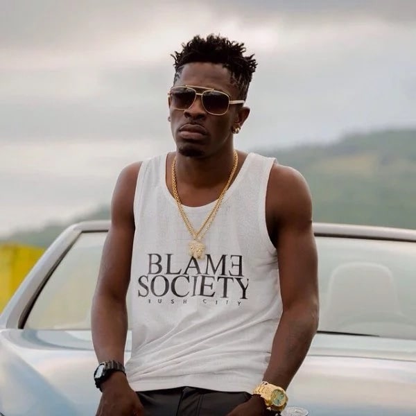 Shatta Wale seated on the bonnet of a car