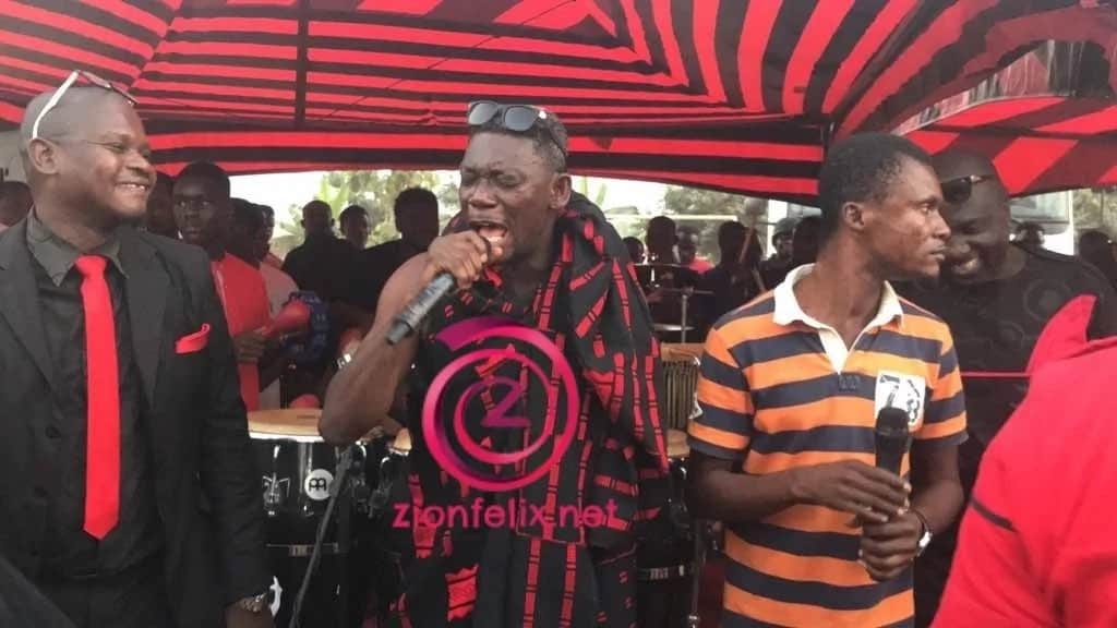 Actor Agya Koo clad in traditional funeral cloth, sings at a funeral