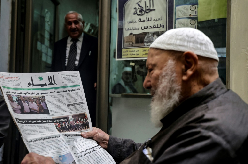A Palestinian man reads a newspaper featuring headlines on the Israeli election