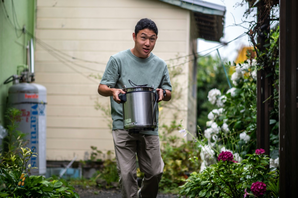 Koichi Miyatsu, 18, carries a pot from his home to a church as part of a monthly charity event for underprivileged children