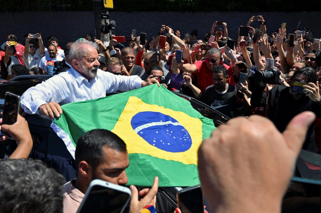 Brazilian former president and candidate for the leftist Workers Party (PT) Luiz Inacio Lula da Silva unfolds a Brazilian flag while leaving the polling station during the presidential run-off election on October 30, 2022