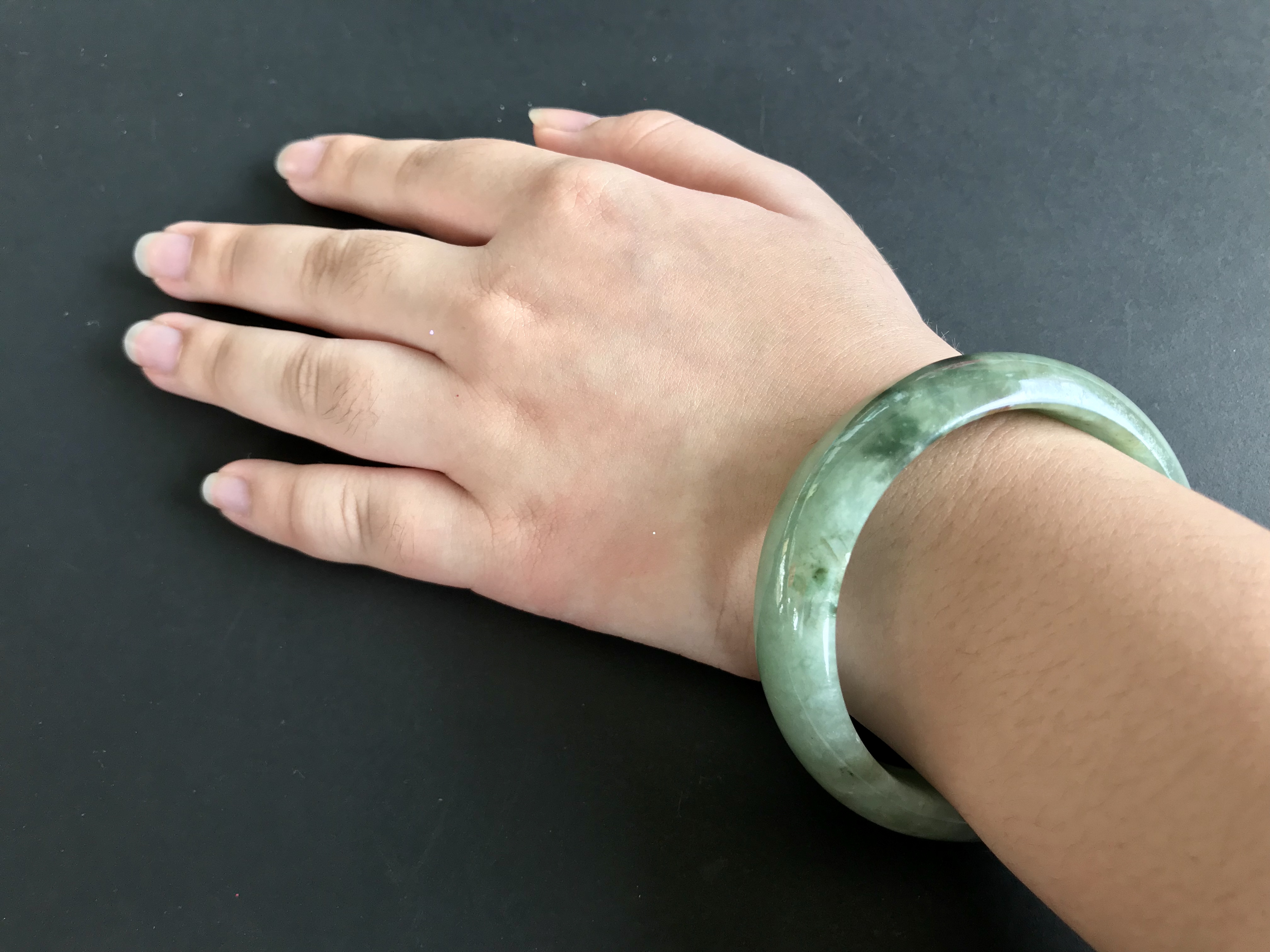 A white woman is wearing a green hololith bracelet
