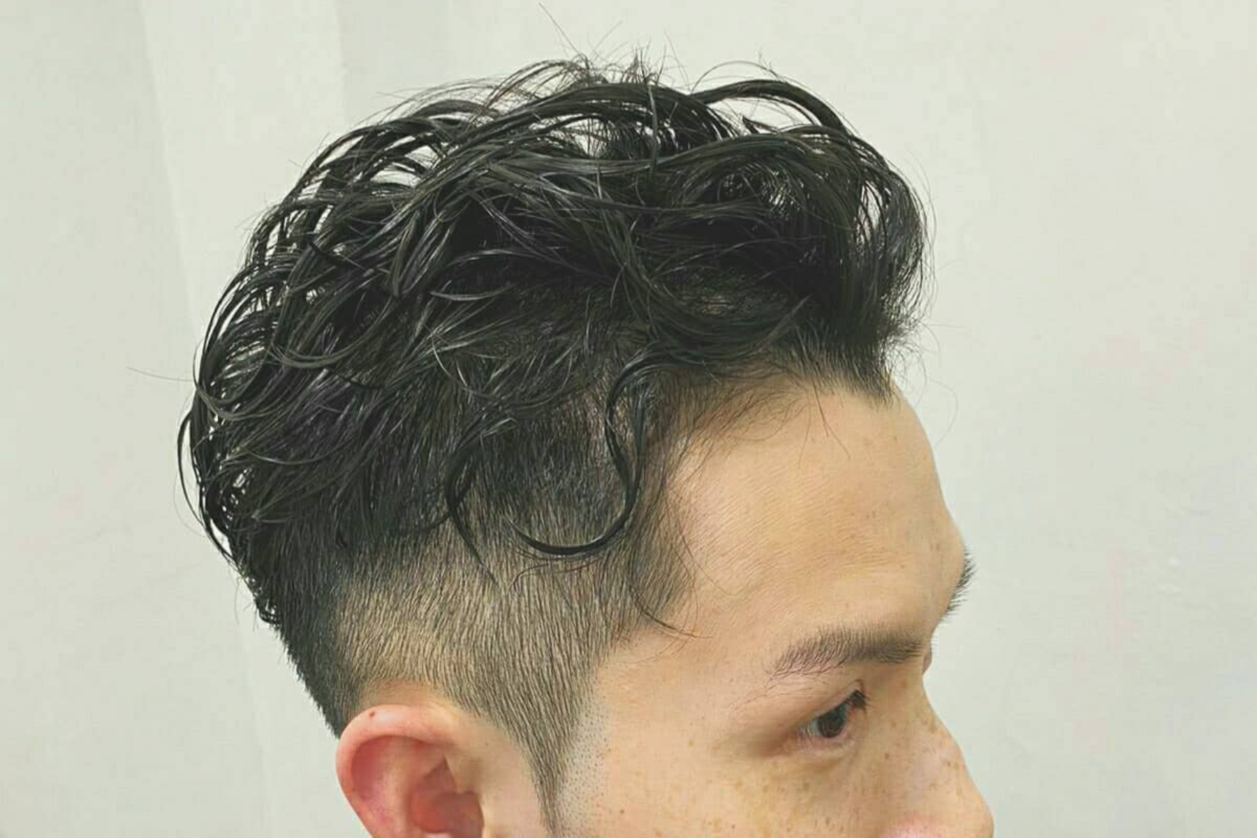 An Asian man with a brushed back hairstyle