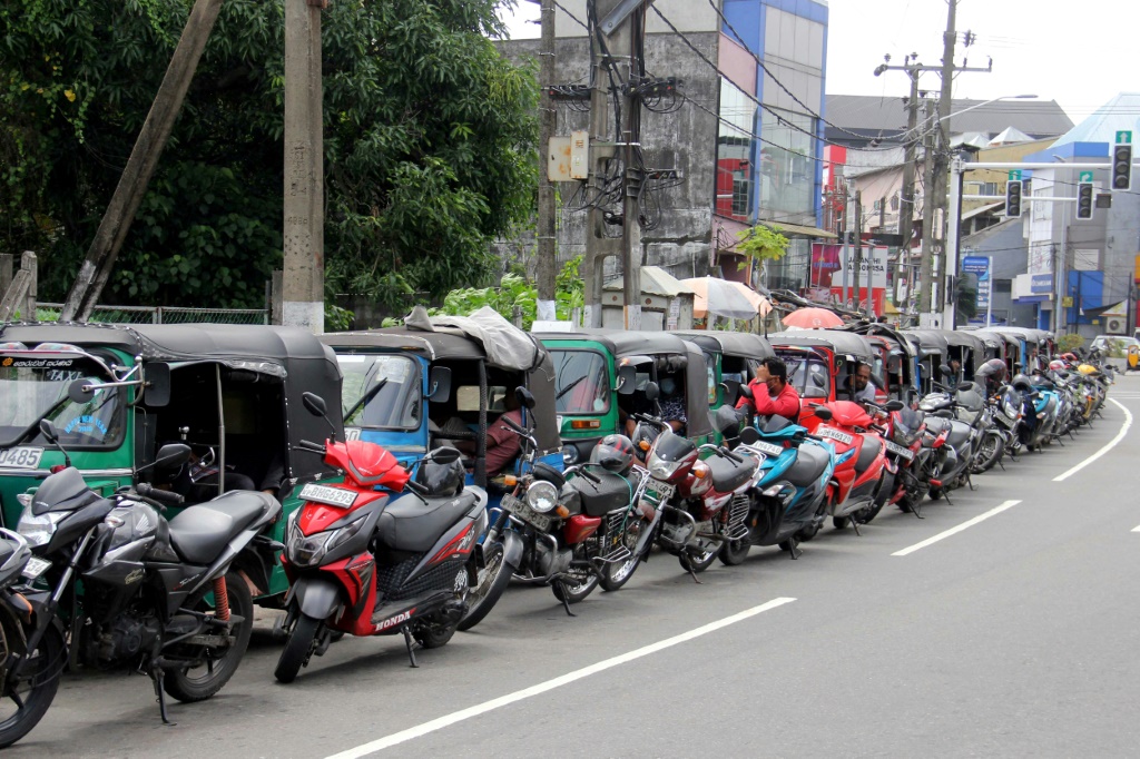 Motorists queue along a street to buy fuel at a fuel station in Colombo on June 26, 2022