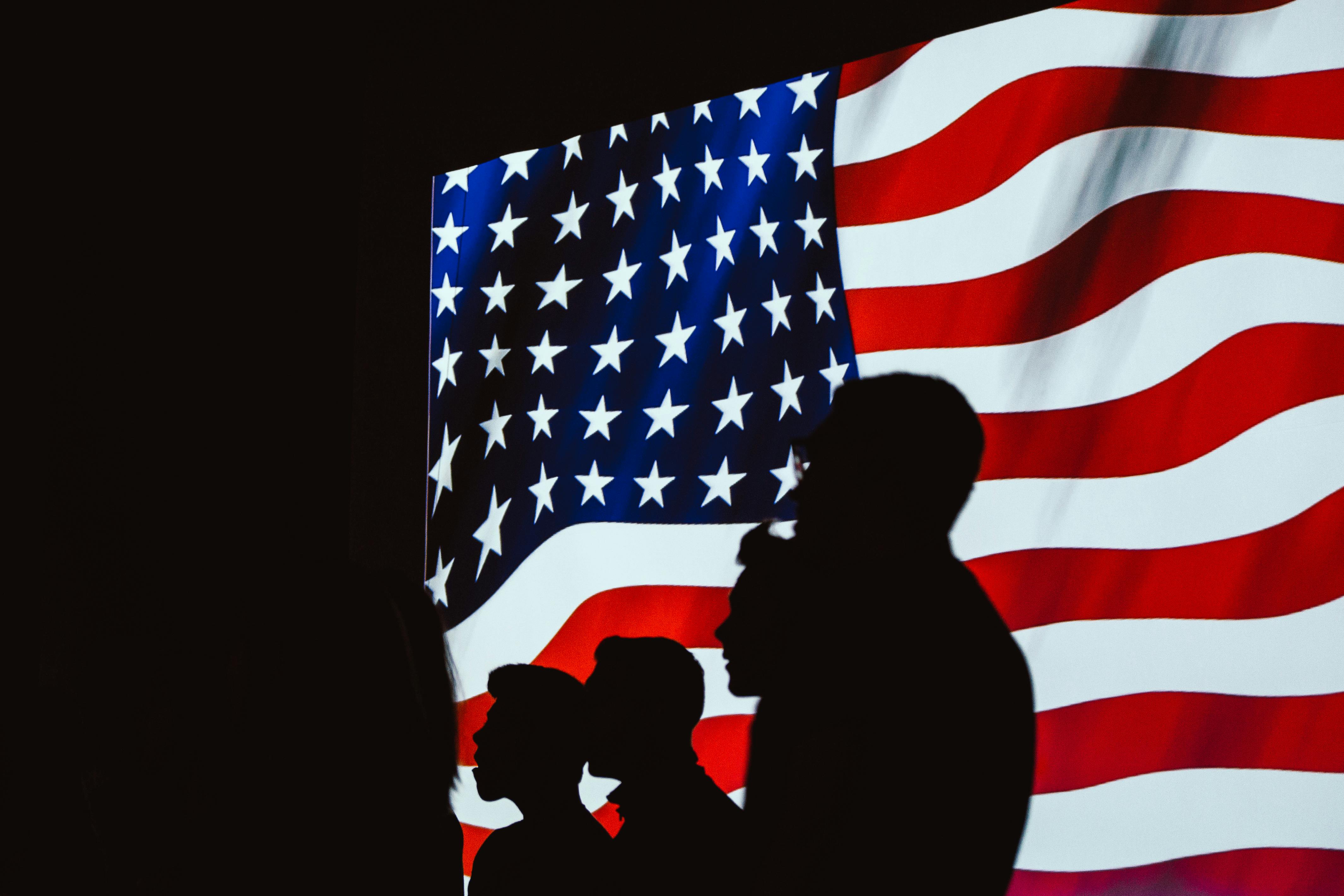 A silhouette of people beside the USA flag