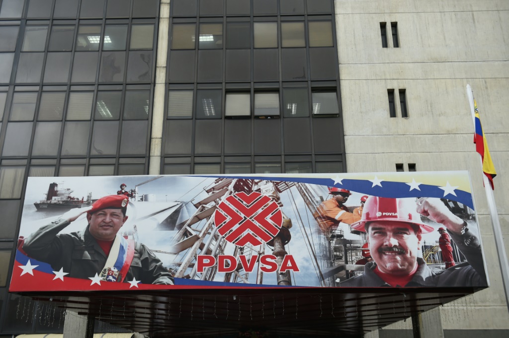 An entrance to the headquarters of Venezuela's state oil giant, known as PDVSA, displays portraits of late Venezuelan President Hugo Chavez (L) and current President Nicolas Maduro (R)
