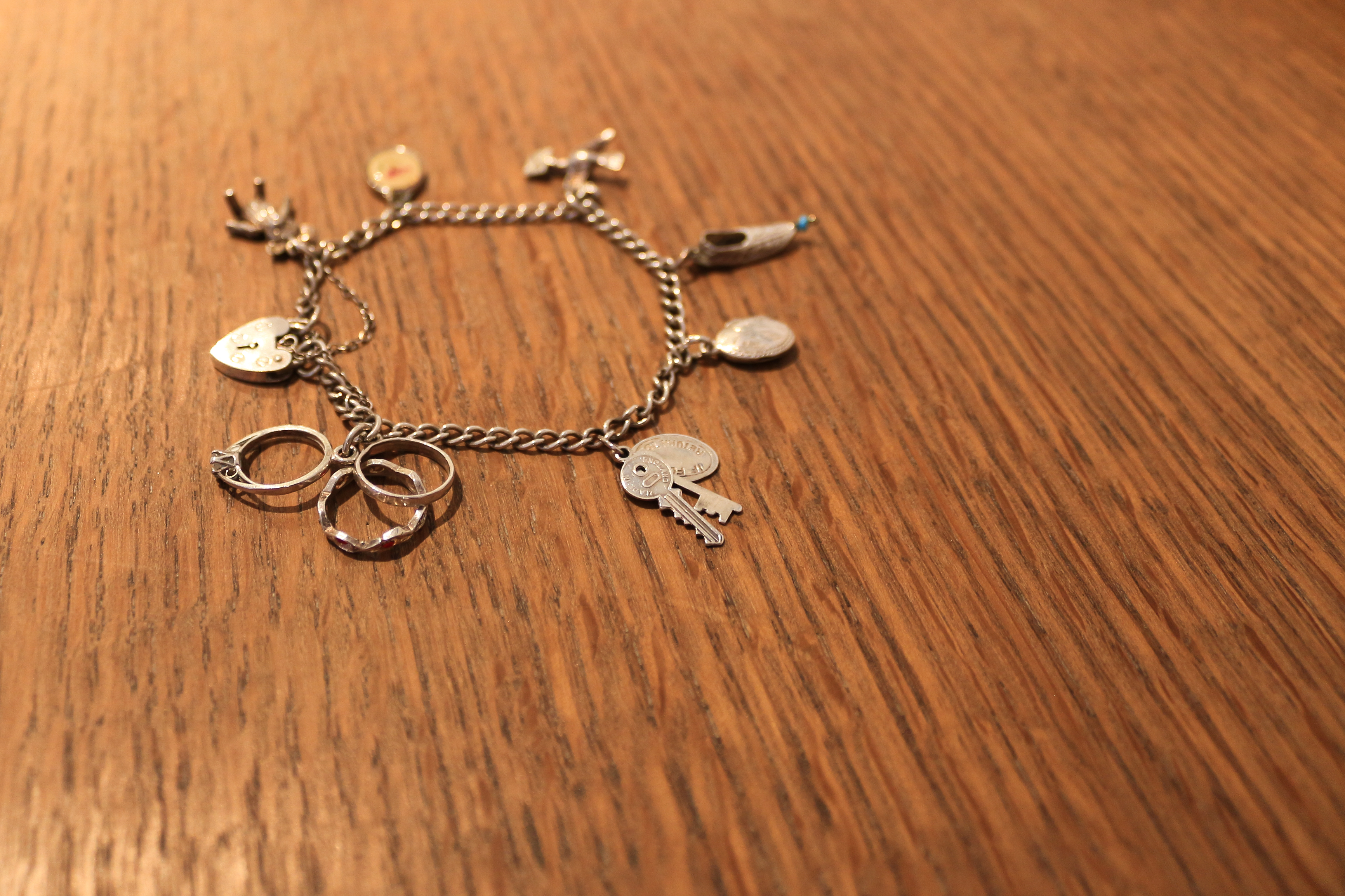A charm bracelet lies on a wooden table